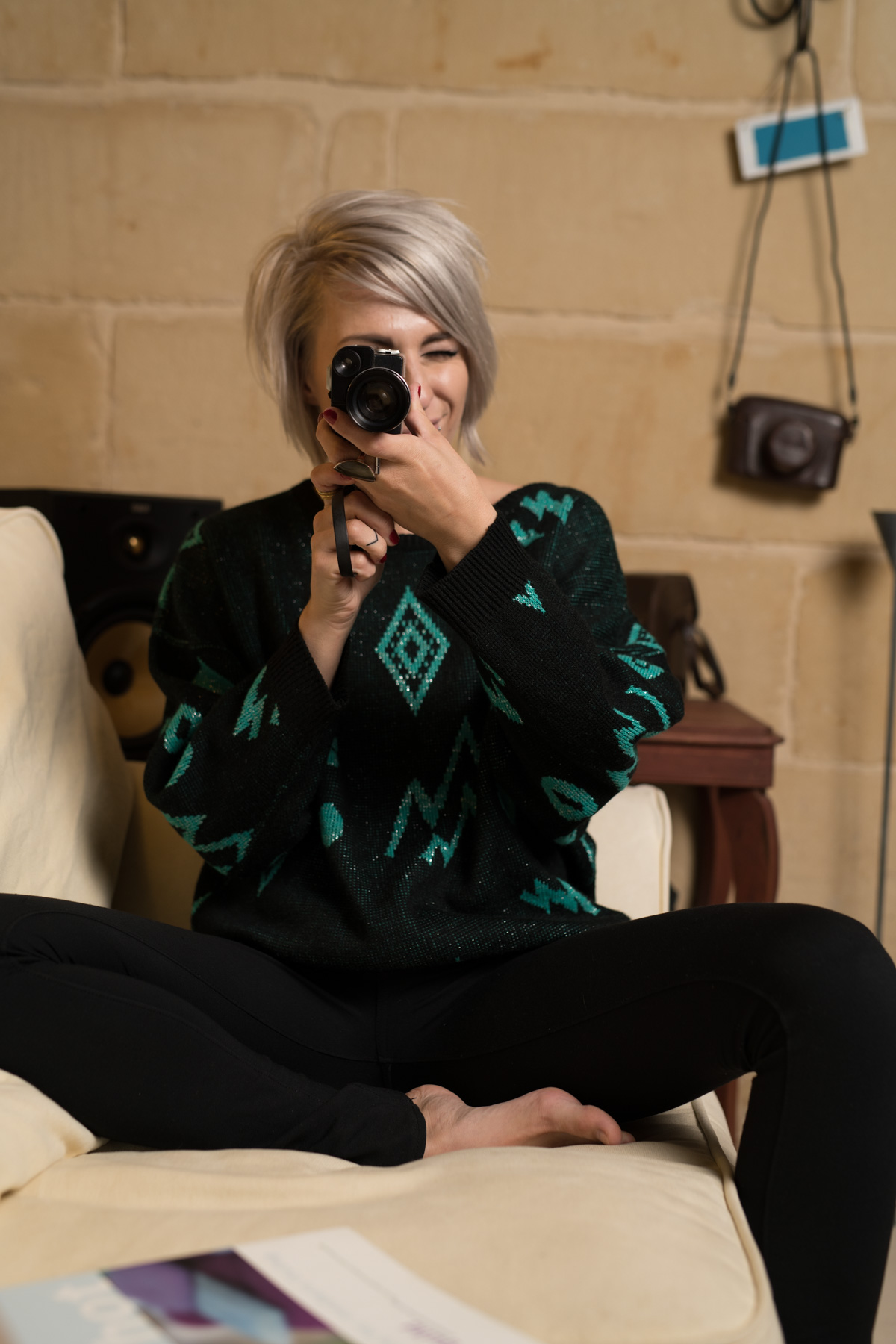 Model, Sacha, wearing the retro black and green sweater and looking through a vintage camera.